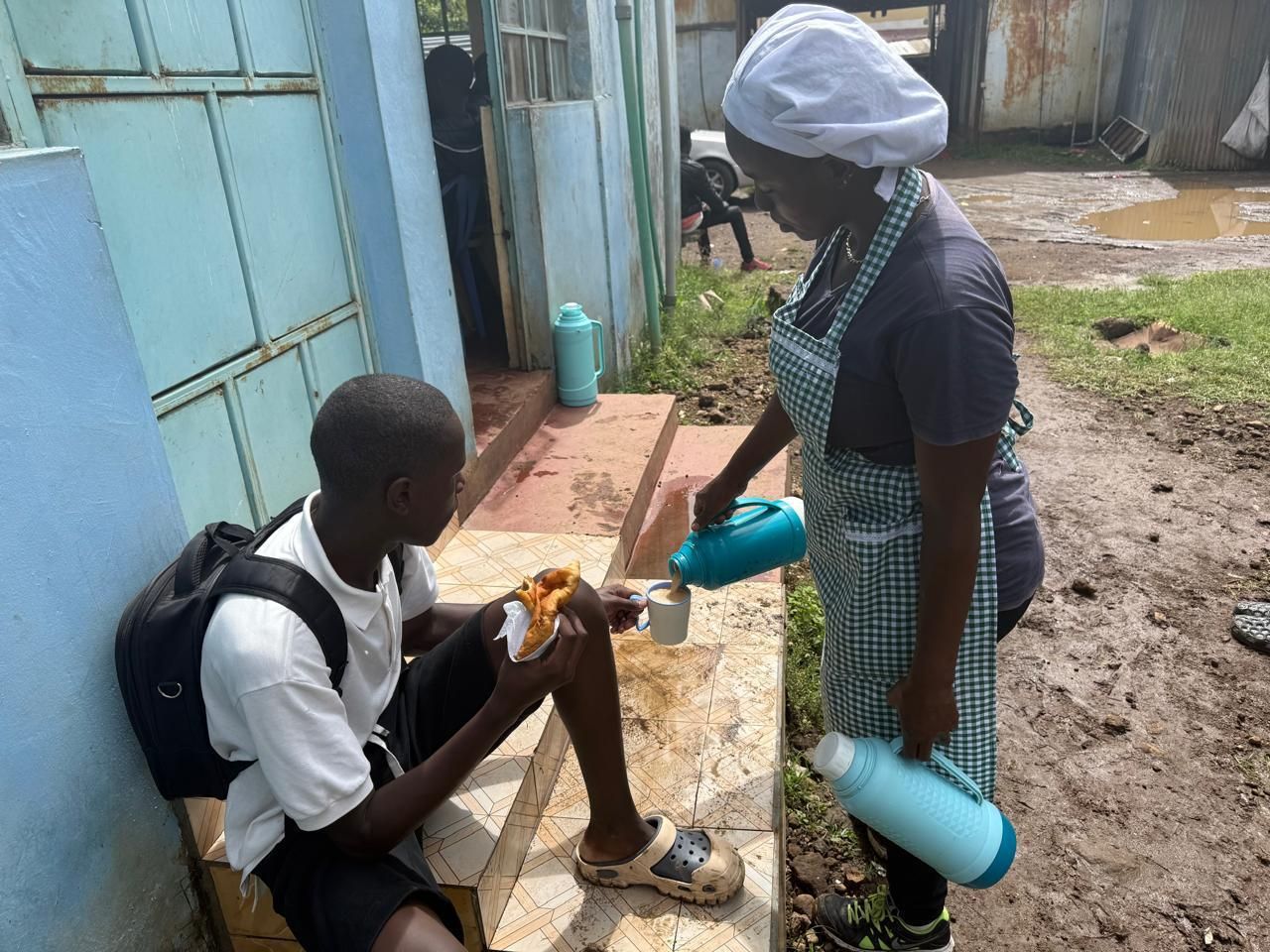 Volunteer serving tea to a boy